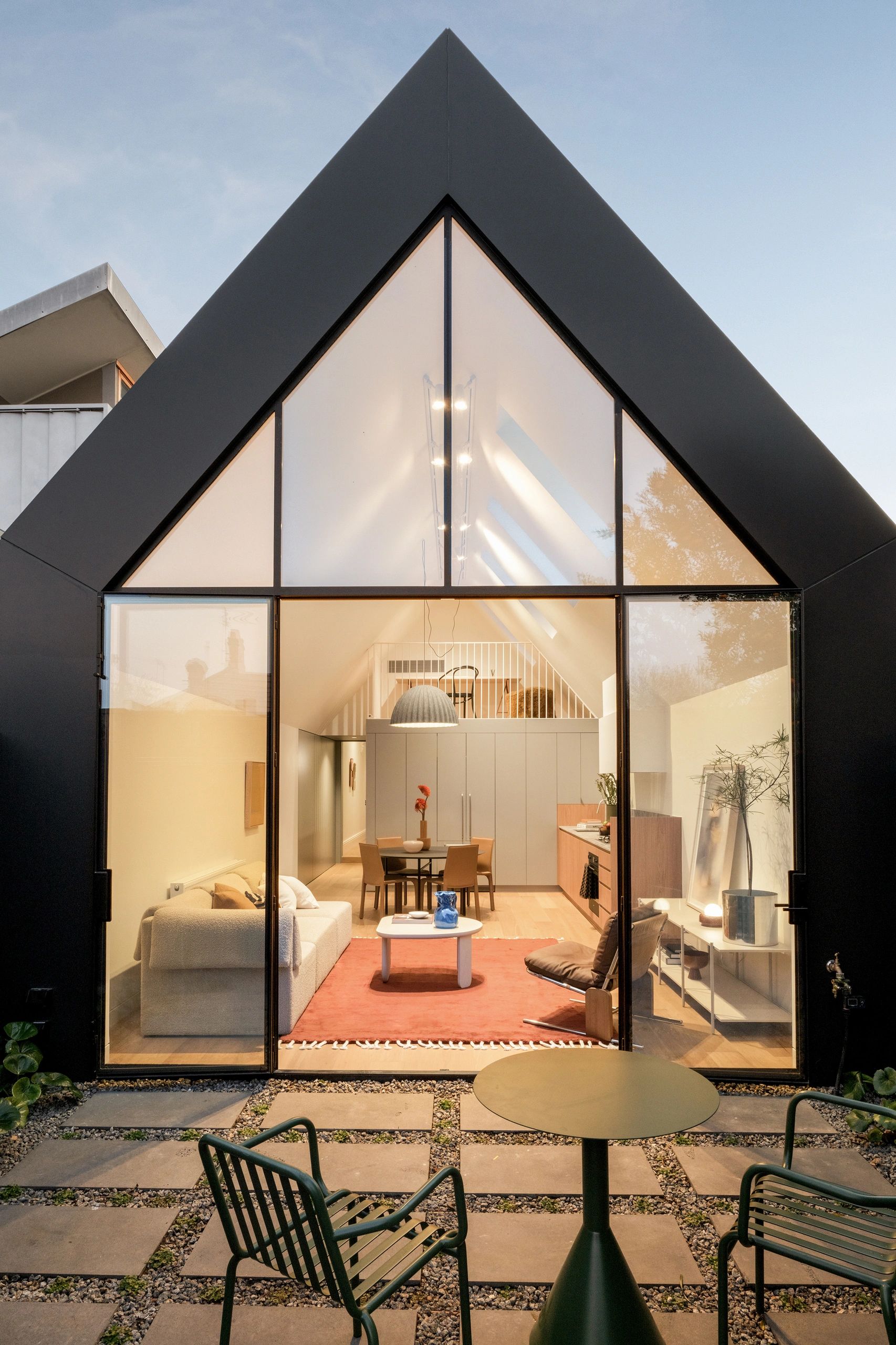 Modern A-frame house with large glass facade showing cozy interior.