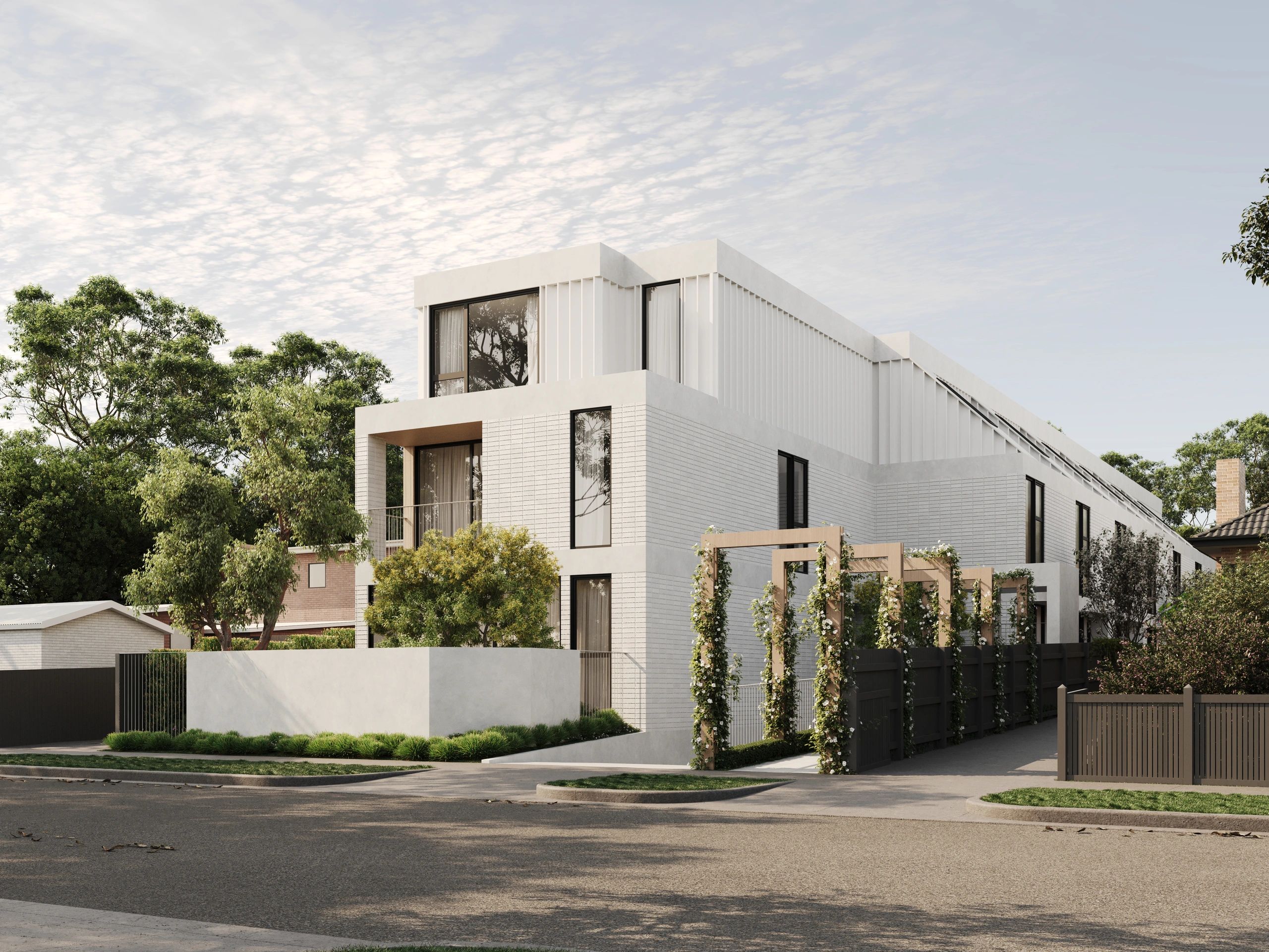 Modern white brick building with large windows and greenery around.