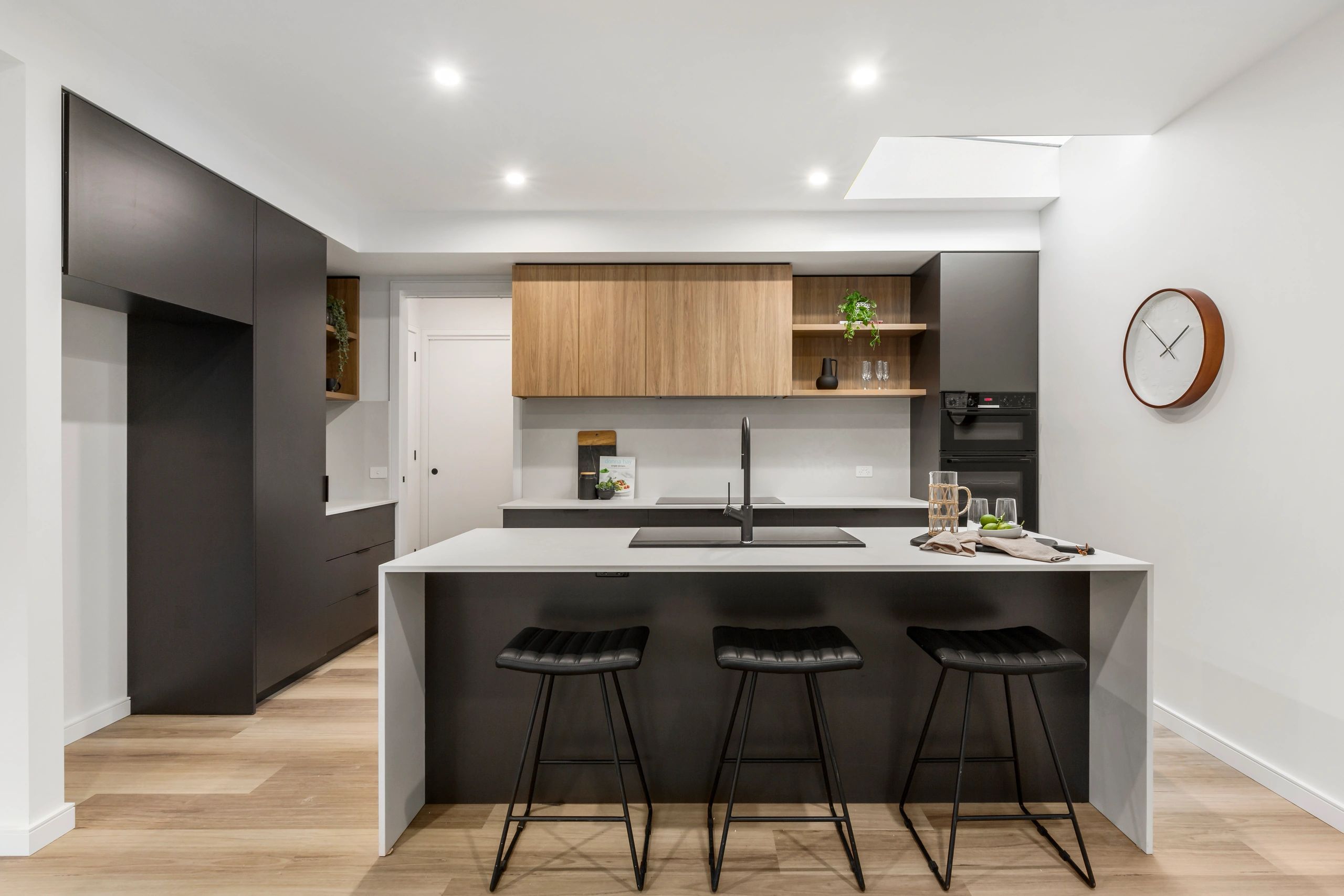 Modern kitchen with black and wood cabinetry and a minimalist island.