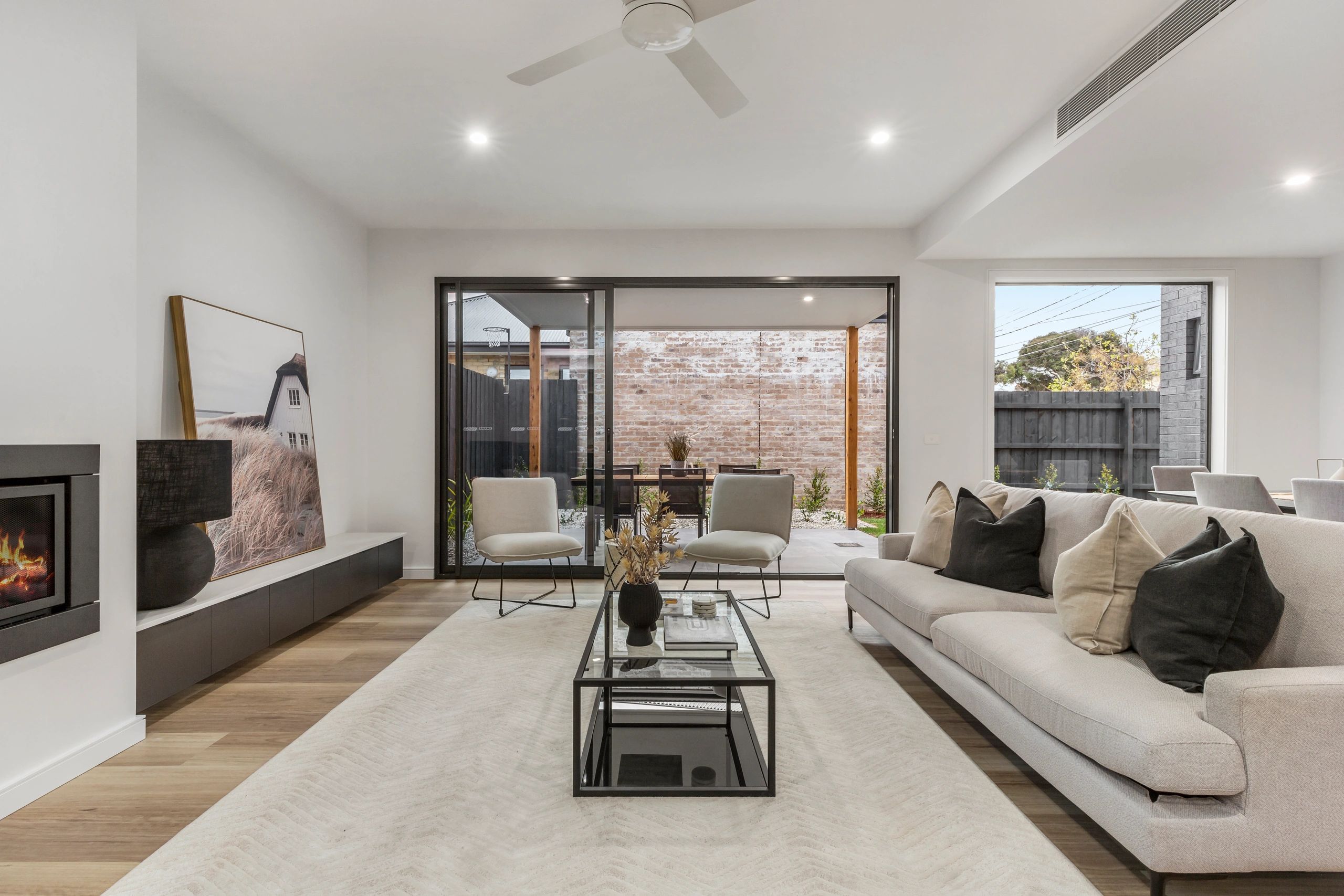 Modern living room with neutral tones and glass coffee table.