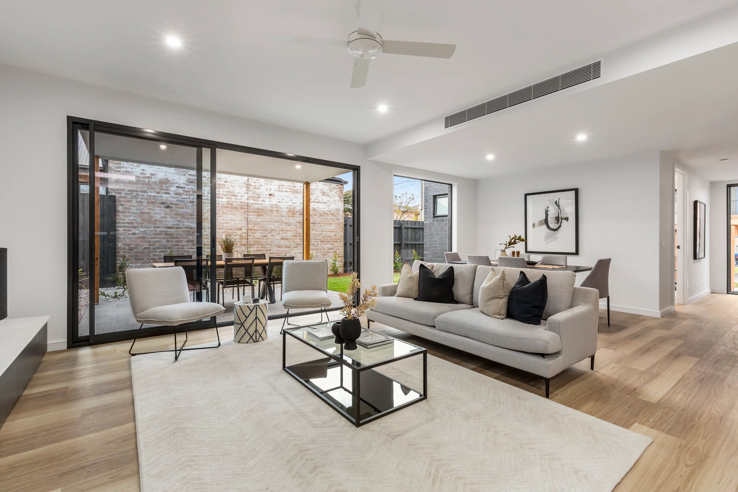 Modern living room with neutral tones and large glass doors leading to an outdoor patio.