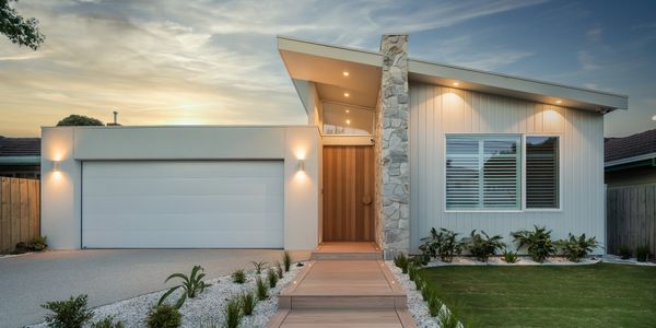 Modern single-storey home design with white cladding, a stone feature wall, and timber entry. 