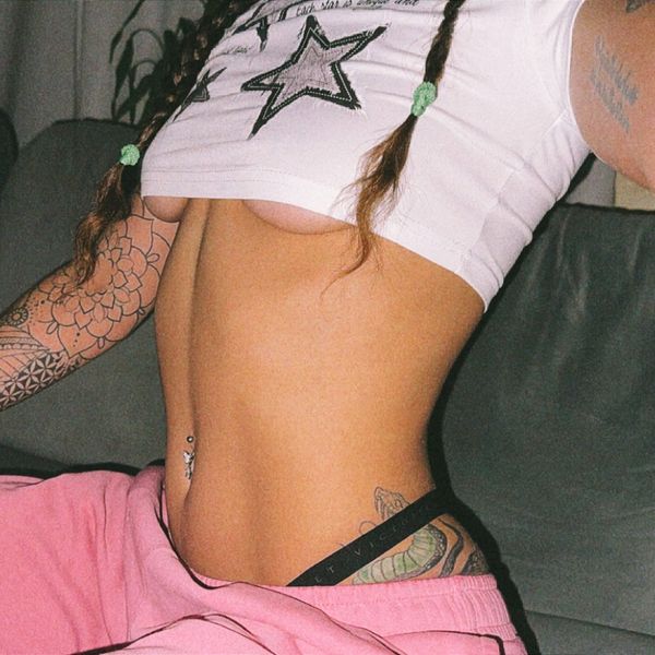 Tattooed person in pink pants lifting star-printed crop top.