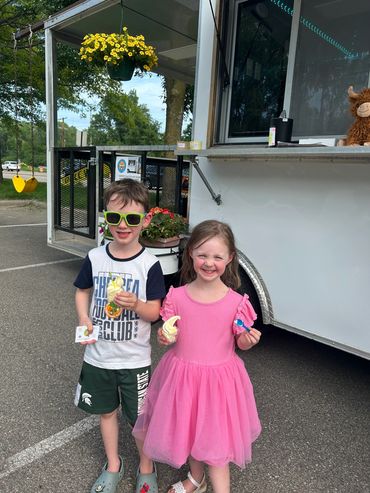 Two children holding ice cream and toffee in their hands 