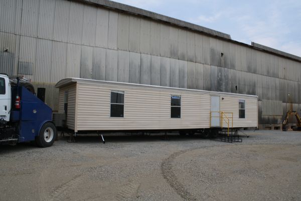 Mobile office trailer parked outside a large industrial building.