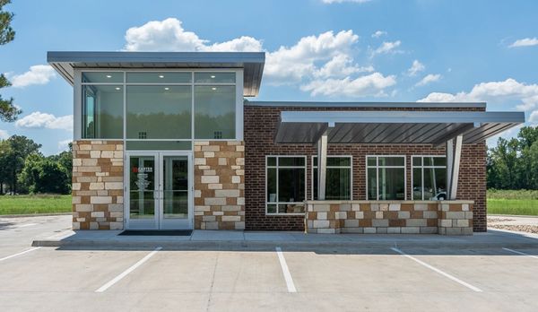 Modern commercial building with stone and brick facade under a blue sky.