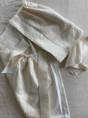Pieces of cream-colored fabric with gathered and sewn details.