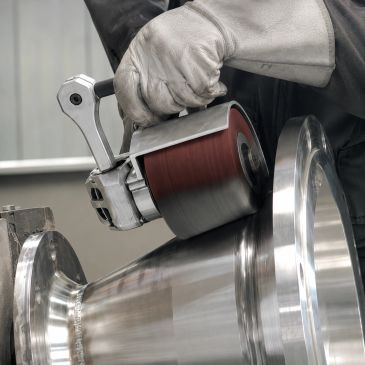 Worker polishing metal surface with grinding tool.