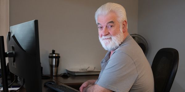 A graphic designer works at his computer on custom designs for customers.
