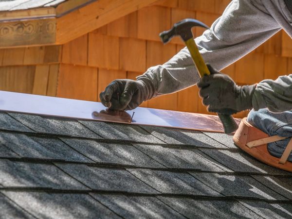 Roofer installing metal flashing on roof