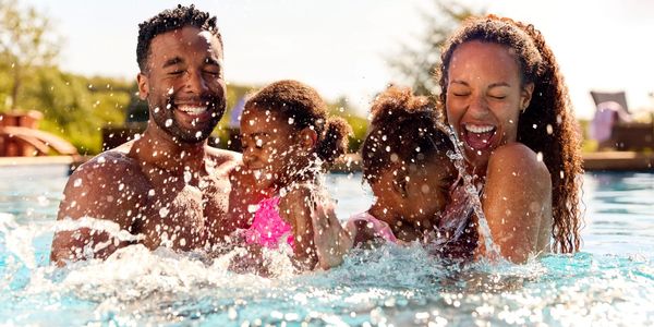 Family joyfully splashing and playing in a swimming pool.