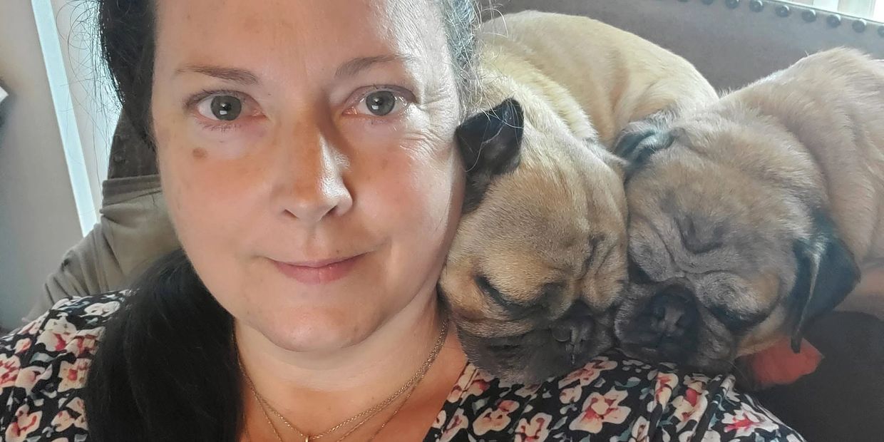 Woman with two pugs resting on her shoulder.