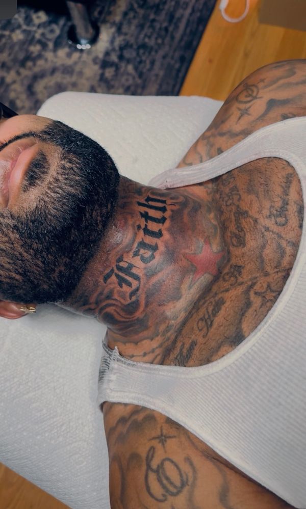 Close-up of a tattooed man lying down, showcasing detailed neck and shoulder tattoos.