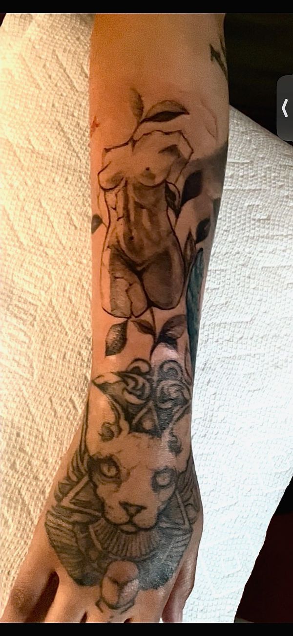 Tattoo of a nude female figure and a cat with geometric shapes on a forearm.
