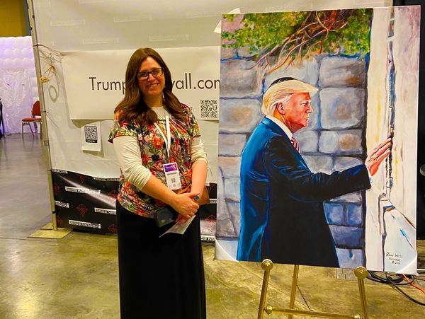 A woman standing in front of a poster of donald trump.