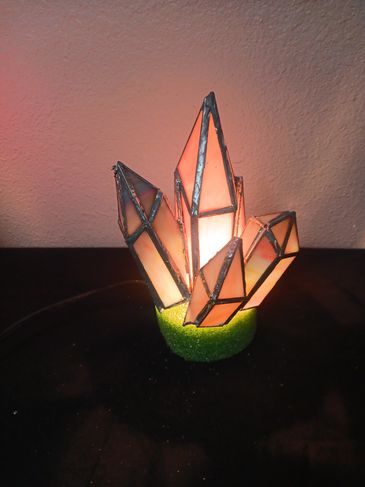 A custom stained glass three dimentional lamp of crystals growing from a rock.