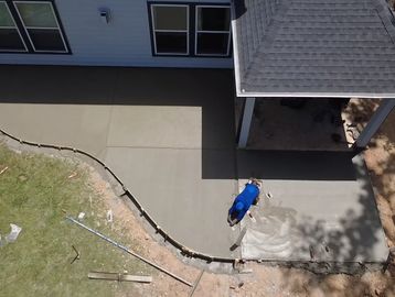 Person smoothing freshly poured concrete patio.