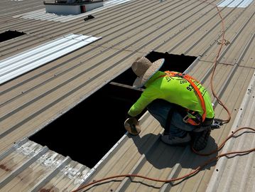 Worker cutting a hole in a metal roof.