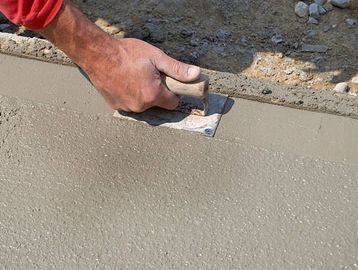Smoothing fresh concrete with a hand trowel.