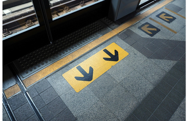 A detailed image of an accessible train platform with tactile indicators and contrasting signs.