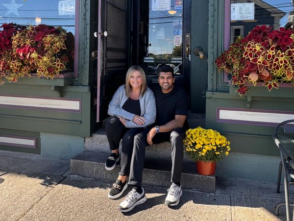 Two people sitting on the steps outside Dante's Kitchen restaurant.