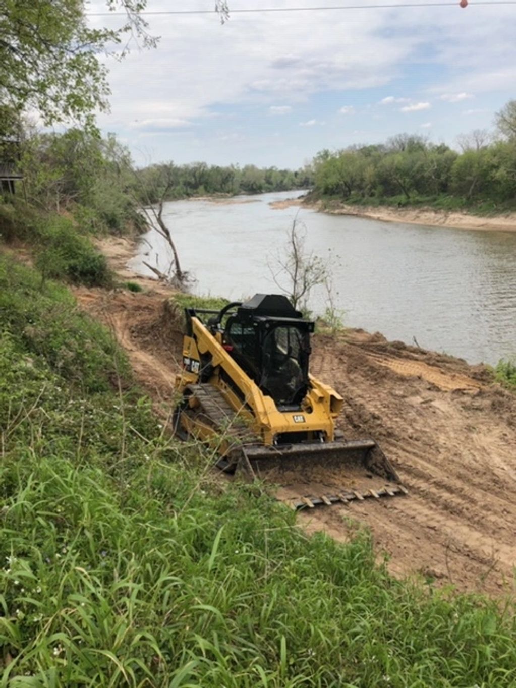 Track machine grading river bank
