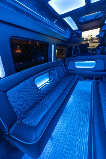 Luxurious limousine interior with blue ambient lighting and leather seating.