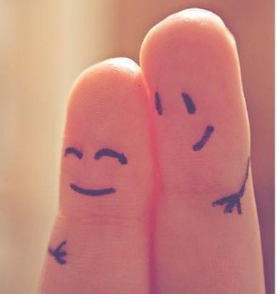 Two fingers with smiley faces and arms drawn on them.