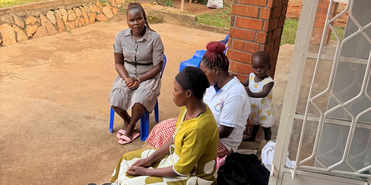 Four people, including a child, sitting and standing outside near a brick pillar.