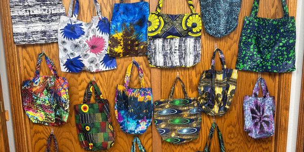 Colorful patterned tote bags hanging on a wooden wall.