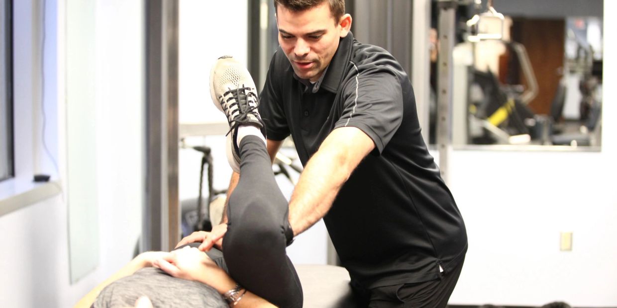 Physical therapist assisting with leg stretch.