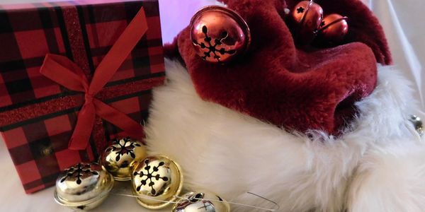 Festive Christmas scene with a red plaid gift box, jingle bells, and a Santa hat.