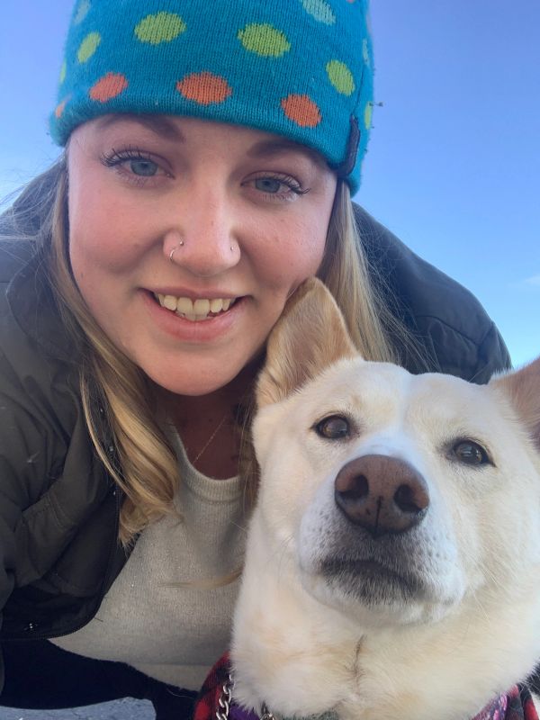 Smiling woman with a dog outdoors.