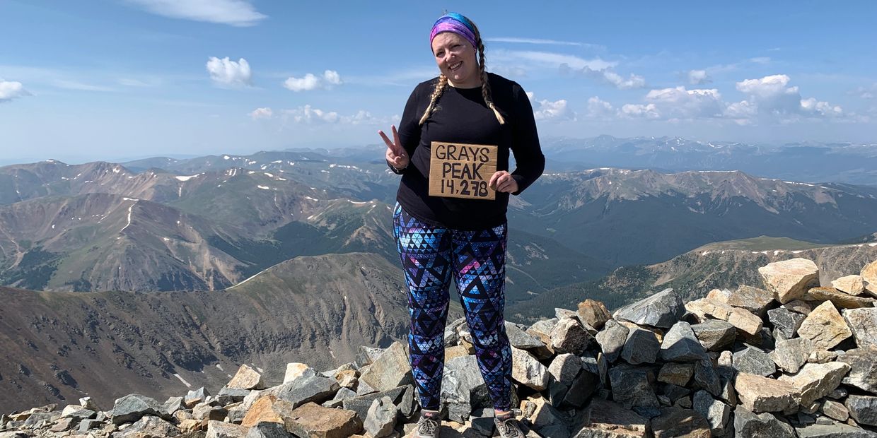 Woman holding a sign on Grays Peak summit.