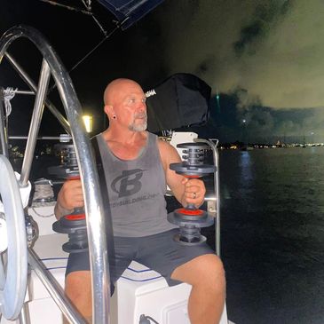Man lifting dumbbells on a boat at night.