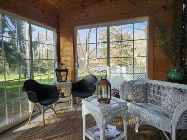 Cozy sunroom with wicker furniture and black chairs.