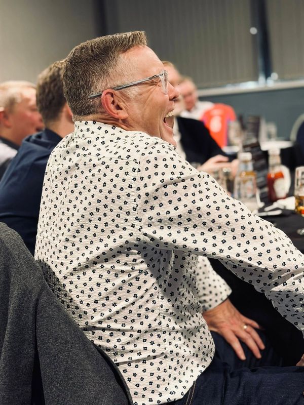 Man laughing joyfully at a social gathering.