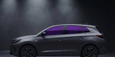 Sleek gray SUV with tinted purple windows in a dark studio.