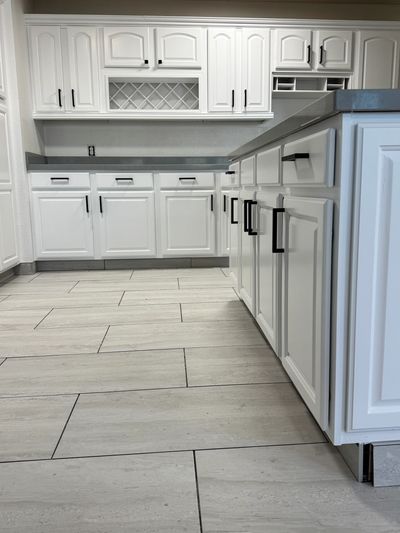 White Kitchen Cabinets with Black Hardware and a gray tile floor