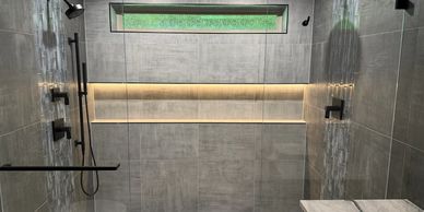Modern dual shower setup with sleek black fixtures and minimalist gray tiles.