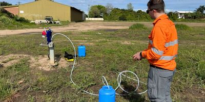 Person in orange outfit testing water pump setup outdoors.