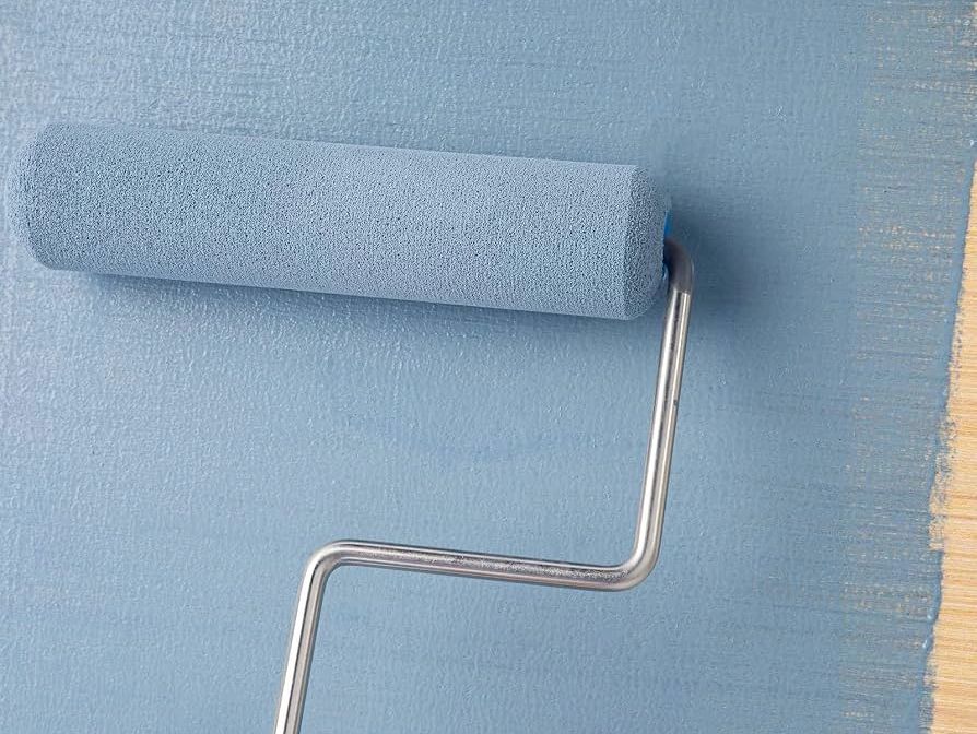 Paint roller applying blue paint on a wall.