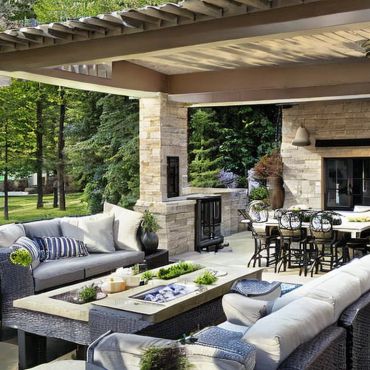 Elegant outdoor patio with comfortable seating and dining area under a covered pergola.