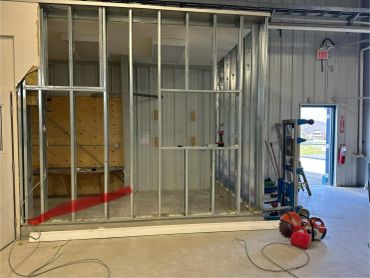 Metal framing for a new interior wall in a warehouse space under construction.