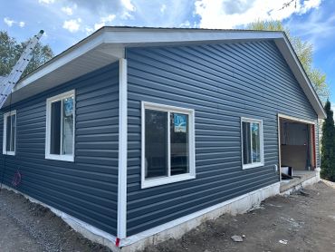 Newly sided house with dark blue exterior and white trim.