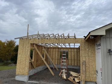 Wooden frame construction of a building under a cloudy sky.