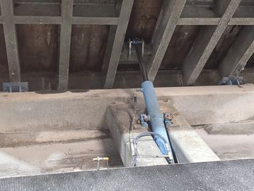 A blue hydraulic jack lifting a heavy concrete structure.