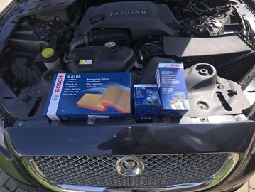 Jaguar car engine with Bosch air filter and spark plug boxes placed on it.