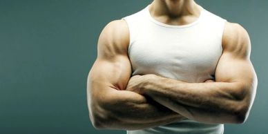 Muscular man with crossed arms in a white tank top.