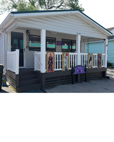 Small white house with a porch decorated with artwork and a purple sign.